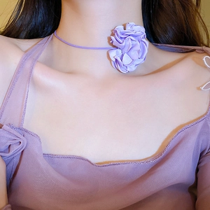 Detailed view of a purple fabric flower choker necklace worn on a model neckline