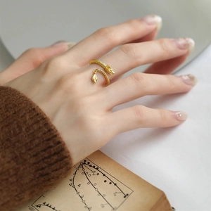 Close-up of a golden dragon ring with detailed scale engraving on a female hand