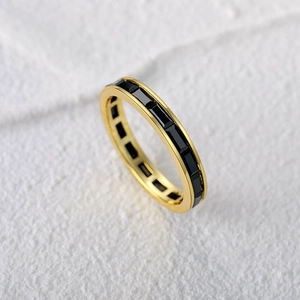Detail of gold plated ring with channel set rectangular black gemstones in a row