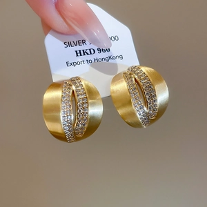 Macro shot of brushed 18K gold C-shaped earrings with fine cubic zirconia inlay detail