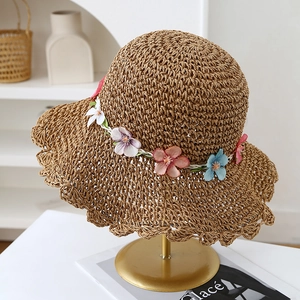 Dettaglio cappello di paglia intrecciato a mano con fiori colorati e tesa ondulata