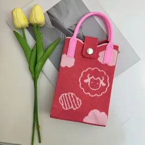 Close-up of red knitted phone bag with white lamb pattern and pink handle detail