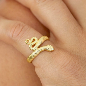 Macro shot of gold snake-shaped ring showing intricate scale textures on a model's finger
