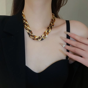 Close-up of gold and tortoise shell chain necklace on model showing link texture