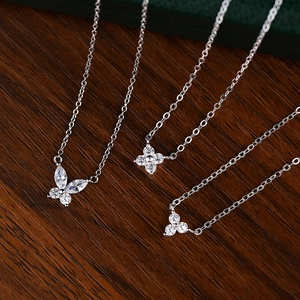 Elegant S925 sterling silver necklaces with clover and butterfly pendants on wood surface