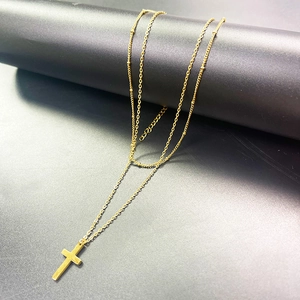 Dettaglio della collana a doppio strato in acciaio inox con croce e piccole perle d'oro