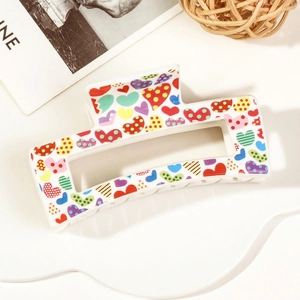 Detail shot of rectangular hair claw clip with colorful heart patterns on a white base