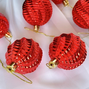 Nahaufnahme roter spiralförmiger Weihnachtskugeln mit Metallic-Finish auf Seide