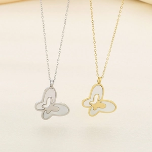 Detailed view of silver and gold butterfly necklaces with white shell inlay pendants