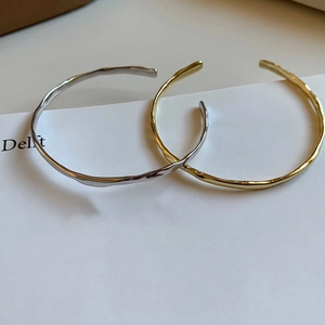 Detail of gold and silver open bangles featuring unique irregular fluid textures