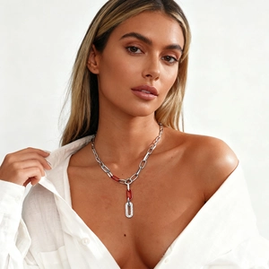 Silver chain necklace with red link and diamond-encrusted oval pendant on a model