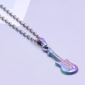 Close-up of a rainbow-plated guitar pendant on a metal chain against a purple background
