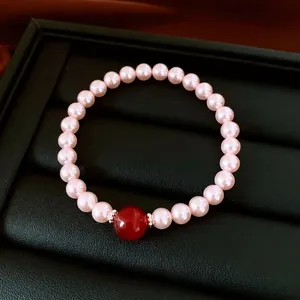 Bracelet de perles élégant avec perle agate rouge sur plateau noir et satin rouge