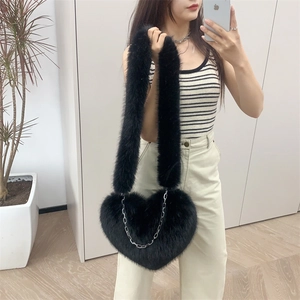 Mirror selfie showing the black plush heart-shaped crossbody bag with silver chain strap