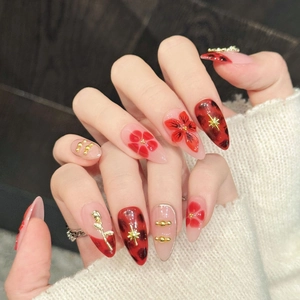 Artistic stiletto press-on nails featuring red floral art, leopard prints, and gold 3D charms
