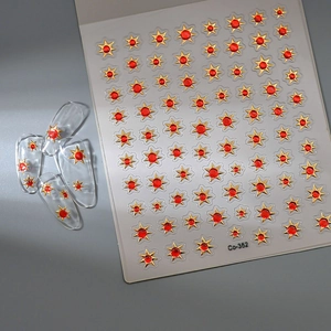 Macro detail of French style 3D gold star and red gem nail art stickers on clear tips