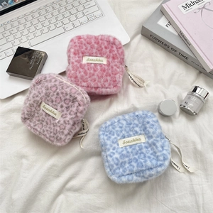 Three plush leopard print sanitary pouches in pink blue and purple on a white bed