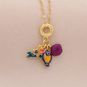 Gold necklace with mermaid, fish, and purple stone pendants on beige texture