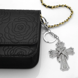 Sparkling rhinestone cross keychain on black floral leather bag with chain strap