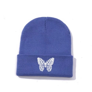 Close-up of white butterfly embroidery on blue ribbed knit beanie hat for winter