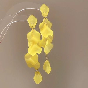 Macro detail of long yellow chiffon flower petal earrings with golden chains