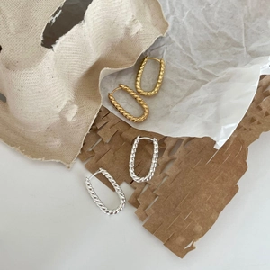 U-shaped twisted rope hoop earrings set in gold and silver finishes on textured paper