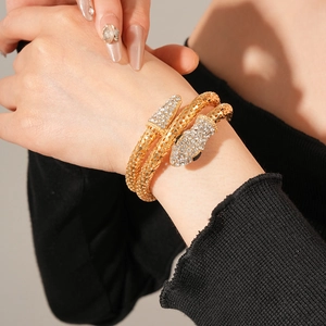 Macro shot of gold snake wrap bracelet with sparkling rhinestones on model's wrist