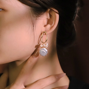 Elegant baroque pearl drop earrings with irregular gold rings shown on a female model