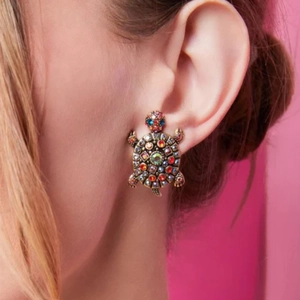 Close-up of vintage gold turtle earring featuring colorful rhinestones on a model's ear