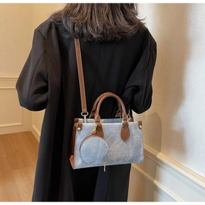 Detail of blue denim textured crossbody bag with brown leather trim and small round coin purse