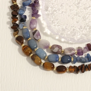 Macro shot of tiger eye, amethyst, and blue stones with gold metal spacer beads