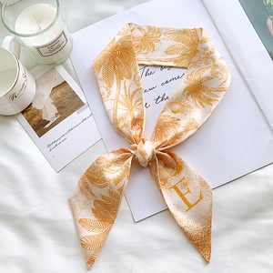Close-up of orange and cream silk scarf with palm tree pattern and letter E detail