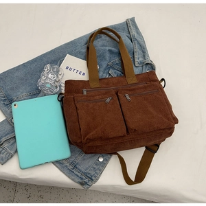 Brown corduroy tote bag with dual front zipper pockets on a casual denim background