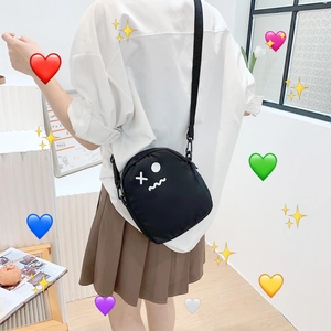 Détail du sac bandoulière en nylon noir avec imprimé visage minimaliste et sangle réglable