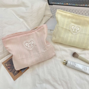 Macro detail of knit cosmetic bags with lace heart patches and bow patterns on white cloth