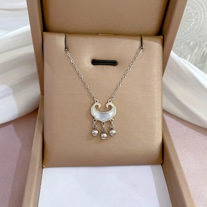 Detail view of a silver Ruyi lock pendant with white shell inlay in a beige jewelry box