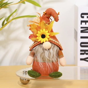 Detail of autumn gnome plush with sunflower and maple leaf on warm indoor background