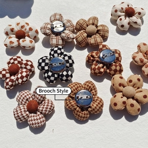 Retro plaid and polka dot fabric flower brooches with metal pins on white textured background