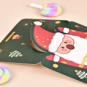 Detail view of 3D pop-up Santa Claus Christmas card with gold tree patterns and smooth texture