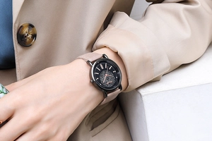 Gros plan d'une montre femme élégante avec cadran étoilé noir et bracelet en cuir beige