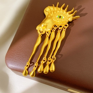 Detailed macro view of Surrealist golden eye brooch with flowing teardrop metal fringe