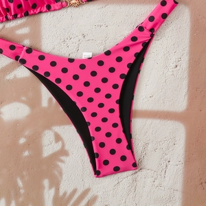 Macro shot of high-stretch hot pink bikini bottom with black polka dots and fabric label