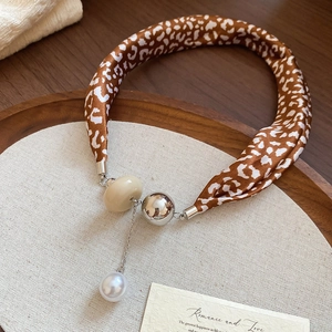 Détail du collier avec perle imprimé léopard et pendentif perle sur plateau bois