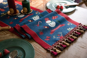 Close-up of blue Christmas table runner with snowman patterns and HAPPY HOLIDAYS text
