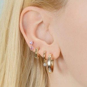 Detail of gold earring set featuring purple teardrop stones and zircon hoops on ear