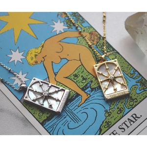 Vintage gold and silver star necklaces with shell pendants on a star tarot card background