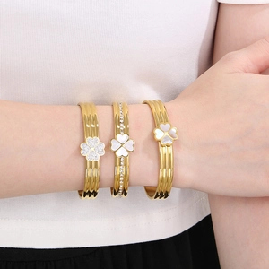 Ensemble de bracelets trèfle doré avec nacre et zircons portés par un mannequin