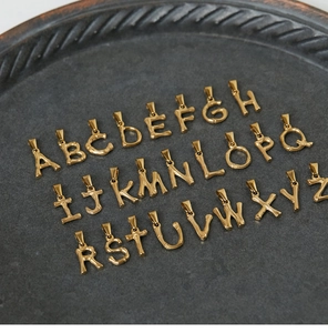 Macro shot of 26 bamboo-style 18K gold plated titanium steel alphabet pendants A-Z