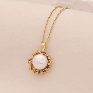 Elegant gold necklace with large white pearl heart pendant on beige curved display