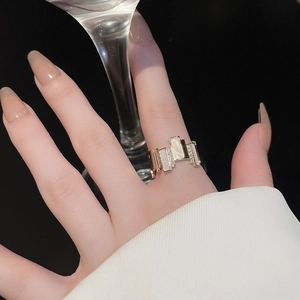 Detail view of gold-plated geometric ring with white rectangular inlay and micro-pave zircons
